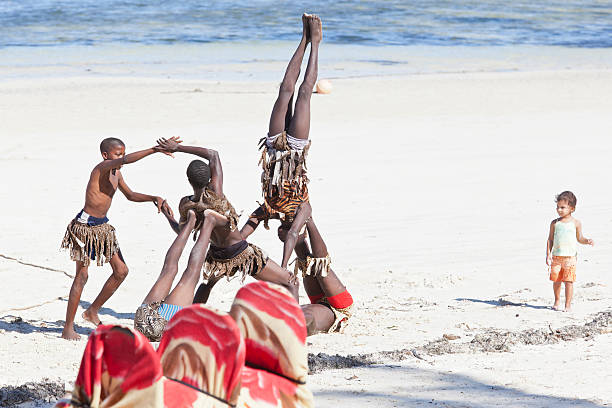 Mombasa, Kenya - May 27, 2012: Young Acrobats at Bamburi Beach in front of the Yul's Restaurant Next to Bamburi Beach Hotel, Mombasa-Malindi Road, Mombasa and one child is watching Young Acrobats.
